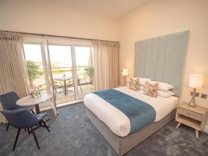 a bedroom with a bed and a balcony with a table at Ocean Sands Hotel in Enniscrone