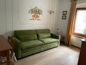 a green couch in a living room with a window at Hotel Miralago Wellness - Adults Only in Molveno