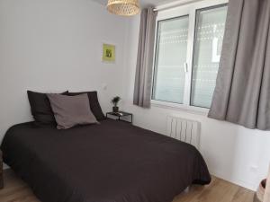 um quarto com uma cama preta e uma janela em Le 4.01 proche centre em Lannion