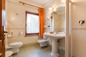 a bathroom with a sink and a toilet and a mirror at Hotel Miralago Wellness - Adults Only in Molveno