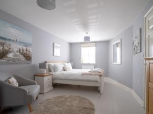 a white bedroom with a bed and a chair at Pass the Keys Lovely 4 bedroom family home with garden parking in Cheltenham