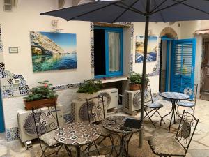 eine Terrasse mit Tischen, Stühlen und einem Sonnenschirm in der Unterkunft Cortile Azzurro in Trapani