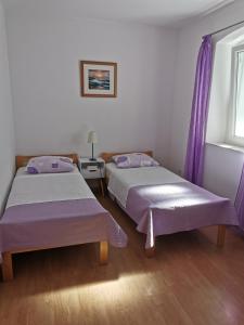 two beds in a room with purple curtains and a window at Radunica Apartment in Split