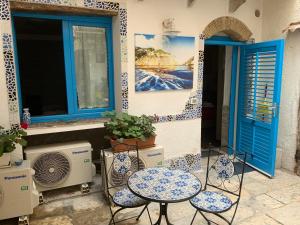 eine Terrasse mit 2 Stühlen, einem Tisch und 2 Fenstern in der Unterkunft Cortile Azzurro in Trapani