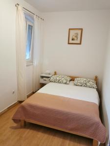 a small bedroom with a bed with a window at Radunica Apartment in Split