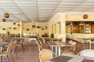 um restaurante com mesas e cadeiras e uma cozinha em Apartamento Luxo no Beach Class Resort Muro Alto 3204 em Porto de Galinhas