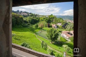 Blick auf ein grünes Feld aus dem Fenster in der Unterkunft Namastè Apartment Città Alta with hills view in Bergamo