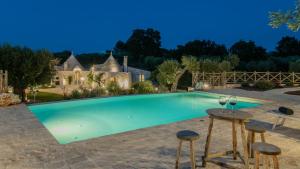 een zwembad met een tafel en twee krukken bij Trulli Ericla Resort in Castellana Grotte