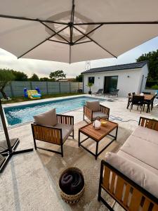 un patio con sillas y una piscina con sombrilla en Studio Isana - avec piscine, en Ambarès-et-Lagrave