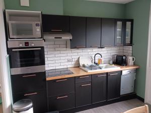 a kitchen with black cabinets and stainless steel appliances at Ker Breizh in Saint-Brieuc