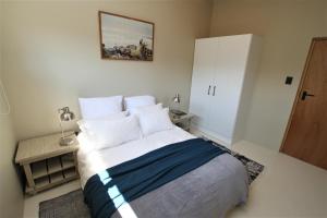 a bedroom with a large bed with white pillows at Garden Flat - Walk To The Beach (no load shedding) in Plettenberg Bay