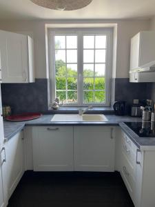a white kitchen with a sink and a window at Loue charmante maison de vacances à 10 mns de Bellême (61) in Saint-Martin-du-Vieux-Bellême +10 photos