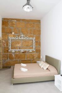 uma cama num quarto com uma parede de tijolos em ARENARIA B&B em Avola