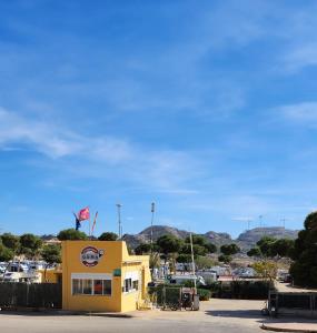 un edificio amarillo con una bandera encima en Bungalow Duemo Camperpark, en Águilas