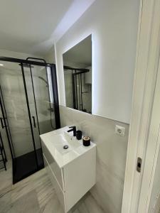 La salle de bains blanche est pourvue d'un lavabo et d'un miroir. dans l'établissement Girasoles Benalmádena Beach, à Benalmádena