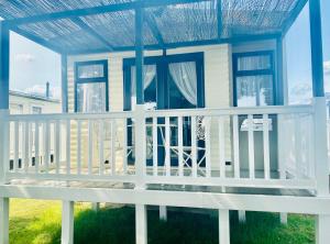 a house with a white porch with a blue roof at Caravan on Mersea Island Away Resorts Quiet Location in East Mersea