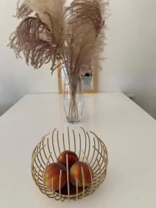 Apartman TESA في Sanski most: سلة من التفاح تجلس على طاولة مع مزهرية