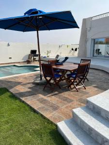 a table and chairs with an umbrella next to a pool at VillaLina Haut Standing Djerba in Ajim