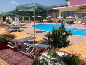 a swimming pool with lounge chairs and an umbrella at Hotel Loggas in Sidhirokhórion