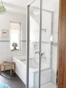 uma casa de banho com uma banheira e uma cabina de duche em vidro. em Dachgeschosswohnung mit 2 Schlafzimmern Nähe Golfresort Weimarer Land em Blankenhain