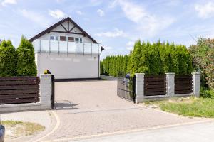 a white garage with a gate and a house at Pokoje gościnne Anna in Rewa