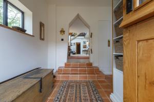 um corredor com uma escada com uma porta de madeira em The Threshing Barn em Forncett Saint Mary