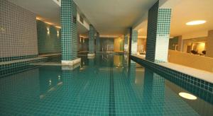 uma grande piscina com azulejos azuis num edifício em Linda suíte de hotel Harry no Rio de Janeiro