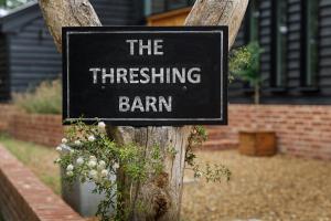 um sinal que diz o celeiro sussurrante num poste de madeira em The Threshing Barn em Forncett Saint Mary