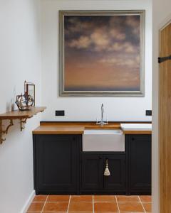 a kitchen with a sink and a painting on the wall at The Threshing Barn in Forncett Saint Mary