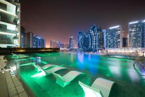 a swimming pool with chairs and a city at night at The Suite Dubai 15 Northside Luxury Living in Dubai