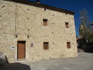 un edificio in pietra con porta marrone e finestre di La Plazuela a Morcuera