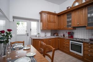 a kitchen with wooden cabinets and a table with chairs at The Rock Guesthouse A 1923 Stone Heritage Home in Meteora in Kalabaka