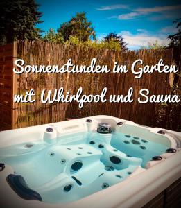 a jacuzzi tub in a garden with a fence at GartenLoft mit Outdoor Whirlpool und Garten in Petershagen