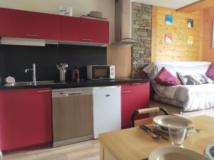 una cocina con armarios rojos y una habitación con cama en *Tout confort*4 pers*Centre Isola 2000, en Isola