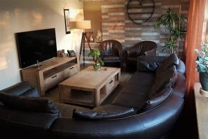 sala de estar con sofá de cuero y TV en Waterhill's Bed & Wellness en Dinteloord