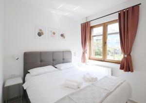 a white bedroom with a large bed and a window at Apartments Maestral in Medulin