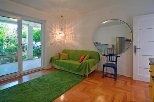 a living room with a green couch and a mirror at Terrace Apartment in Hvar