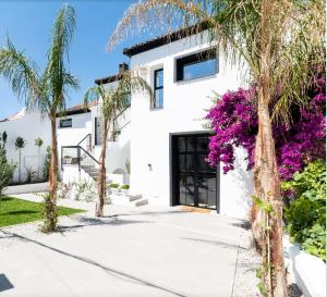 Albuñuelas的住宿－El Molino de Plata，棕榈树和紫色花卉的白色房子