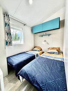 2 camas en un dormitorio con azul y blanco en Bungalow 3 chambres pour 6 pers avec Climatisation Camping 3 etoiles en Samoëns