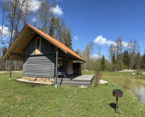 una pequeña cabaña en un campo junto a un lago en Namiņš Guntas, en Uguņi