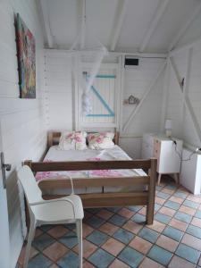 ein kleines Schlafzimmer mit einem Bett und einem Stuhl in der Unterkunft la villa caribéenne de la plage des surfeurs in La Trinité