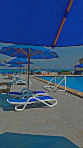 a group of chairs and umbrellas next to a pool at شاليه فندقي بحمام سباحه خاص داخل فندق ايليت ريزيدنس اند اكوا بارك in Ain Sokhna