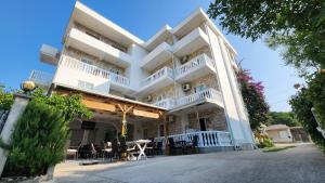 a large white building with a table and chairs at Apartments Cota Guesthouse in Ulcinj