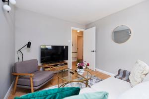 a living room with a couch and a tv at The Mile End Wonder - Entrancing 1BDR Flat with Garden and Parking in London