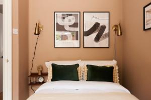 a bedroom with a bed with three pictures on the wall at The Mile End Wonder - Entrancing 1BDR Flat with Garden and Parking in London