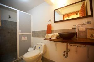 een badkamer met een toilet, een wastafel en een spiegel bij Karibbik Haus Hostel in San Andrés