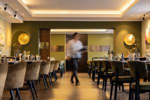 uma mulher a andar por uma sala de jantar com mesas e cadeiras em Gasthaus Stappen em Korschenbroich