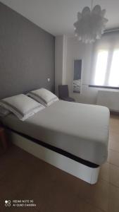 een wit bed in een kamer met een kroonluchter bij La CASUCA De TINA in Prellezo