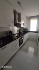 een keuken met witte kasten en een zwart aanrechtblad bij La CASUCA De TINA in Prellezo