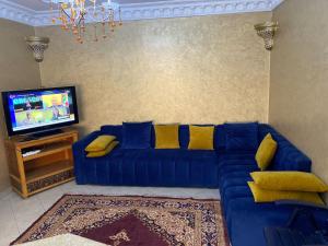 a living room with a blue couch and a tv at ELFA APPARTEMENTS Familiaux in Agadir